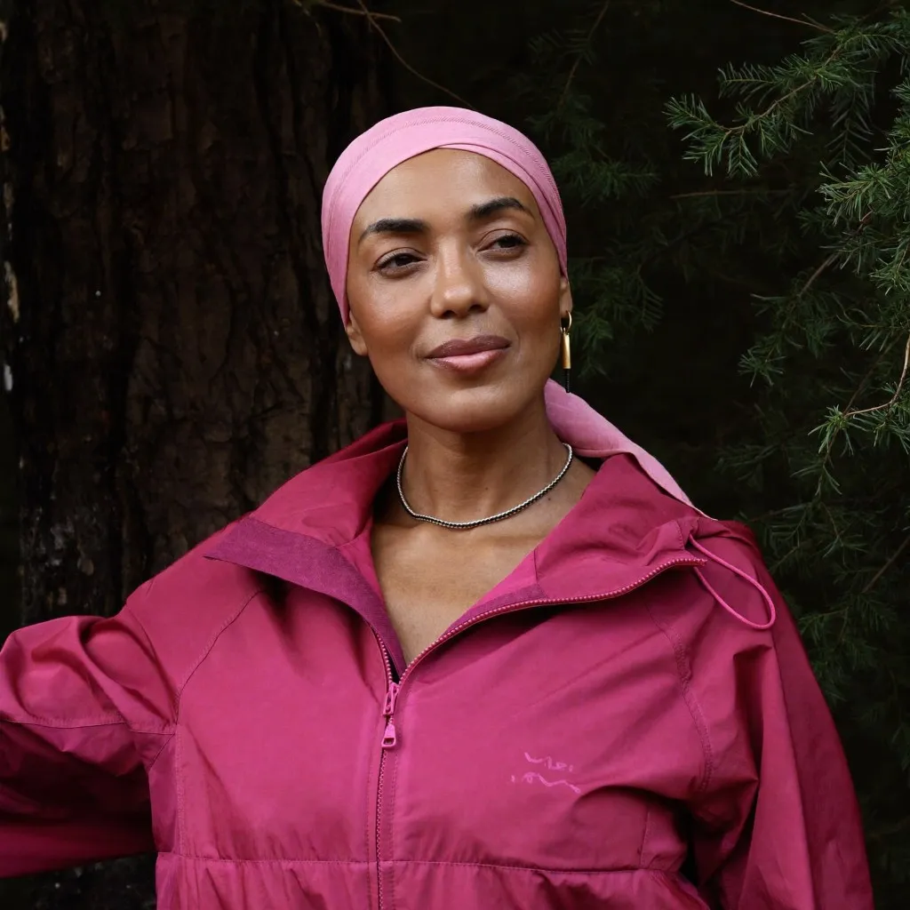 Mujer con un pañuelo rosa, al aire libre.